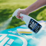 Person spraying the paddle board with the iROCKER SUP Cleaner & Protectant bottle| Bundle